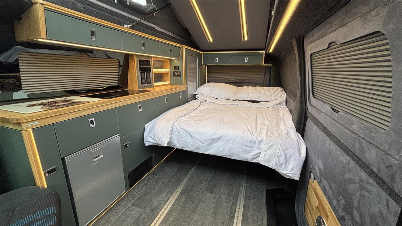 The rock and roll bed made up with a white duvet under warm lights