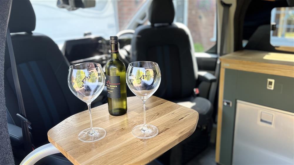 A bottle and two glasses on the oak table between the swivelled seats